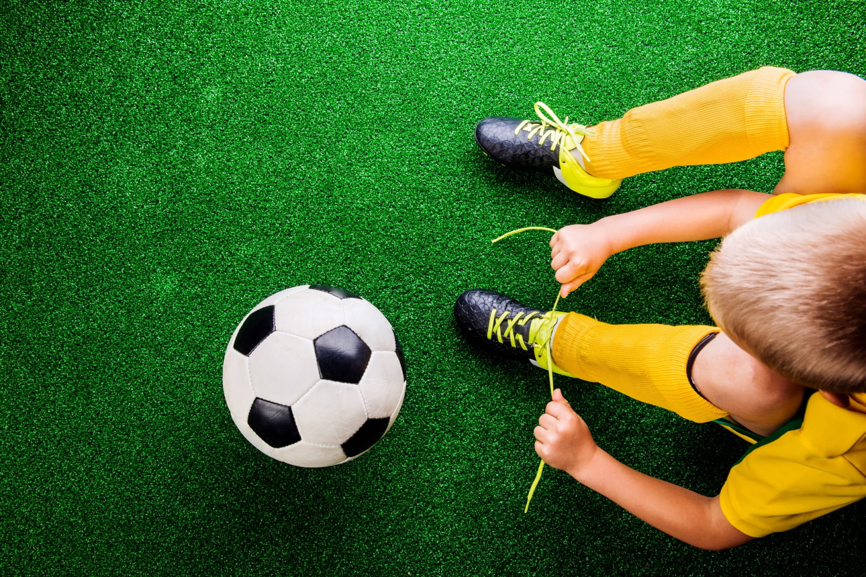 A young soccer player ties their shoe laces.