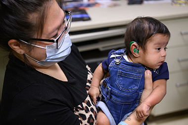 Mother holds child with new hearing aid