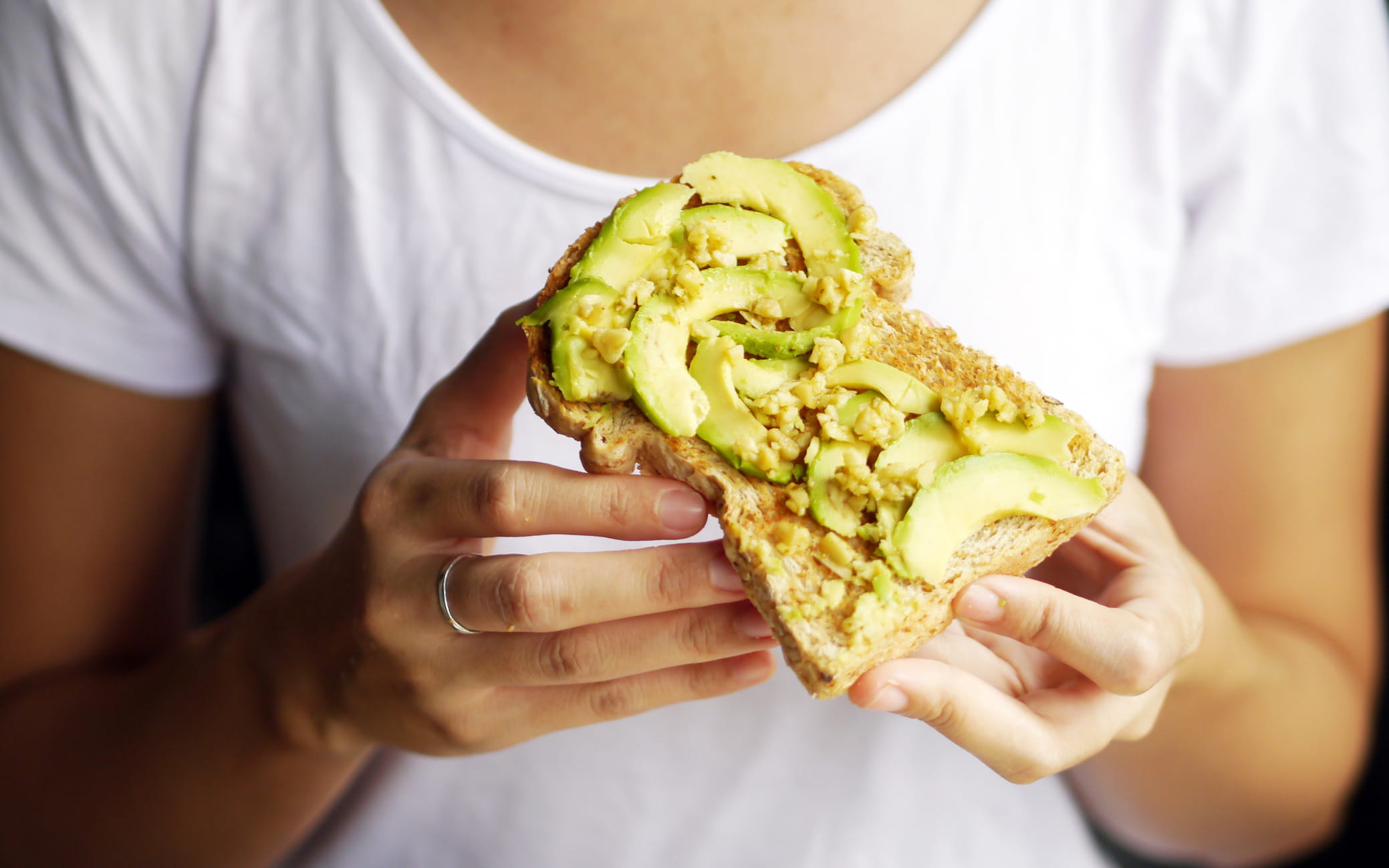 Woman holding a piece of avocado toast
