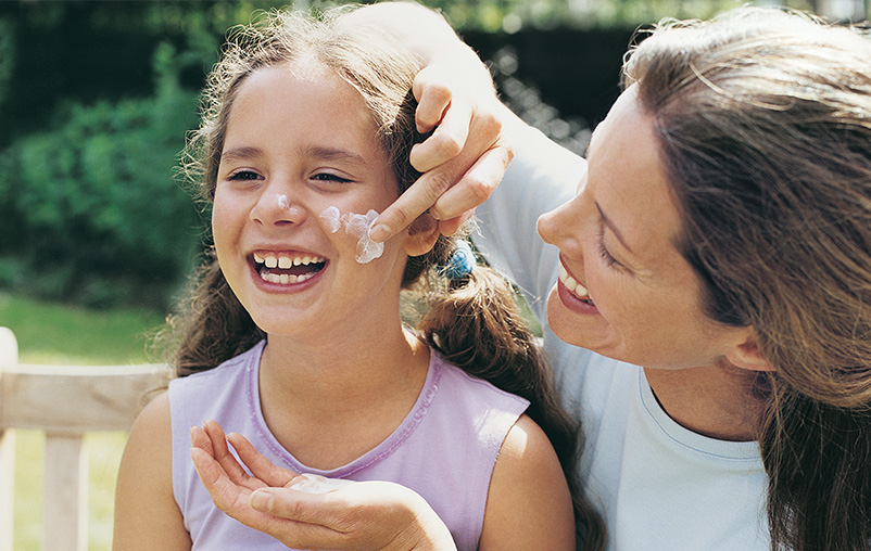 Mom applies sunscreen to her daughter's face