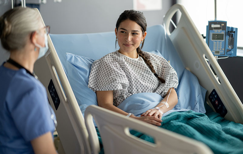 Female surgery patient speaking with her nurse.