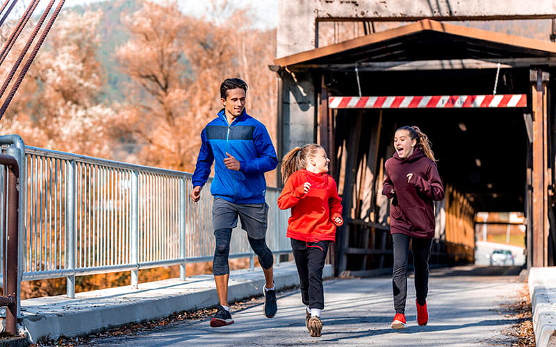 Young father running outside with his two little girls during the winter.