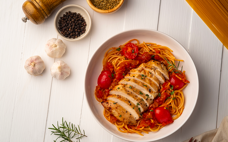 Grilled chicken breast with spaghetti on a white plate